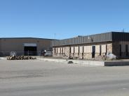 Two brown buildings, pavement, and wood pile